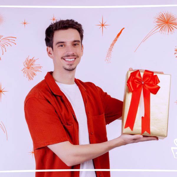 Что подарить мужчине на 30 лет - парень в красной рубашке держит золотую подарочную коробку с бантом