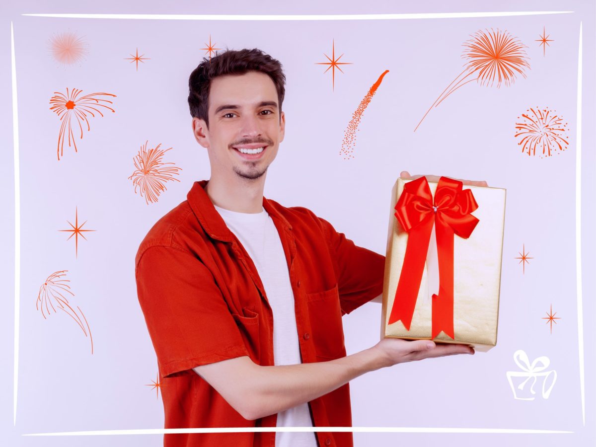 Что подарить мужчине на 30 лет - парень в красной рубашке держит золотую подарочную коробку с бантом